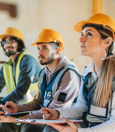 Team of workers in high-visibility vests and helmets attending a safety briefing
